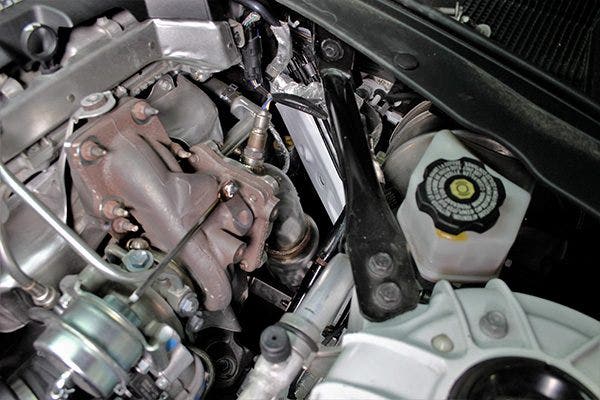 An engine bay view of the downpipe on our 2.0T